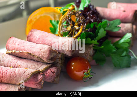 Dünn geschnittenes Fleisch mit Cherry Tomaten, Salat und einem Orangen Stockfoto
