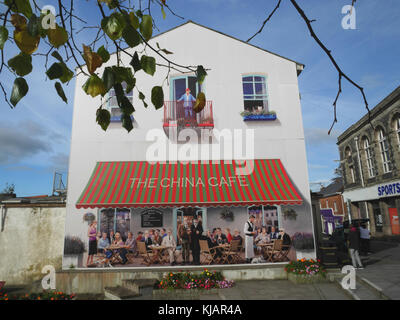 China Cafe Wandgemälde, St. Austell, Cornwall. Daphne du Maurier blickt vom Balkon im oberen Stockwerk aus, während unter 11 weitere tolle und gute Sehenswürdigkeiten der Stadt zu finden sind Stockfoto