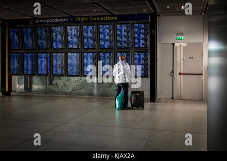 Ein Mann schaut auf die Flugverbindungen in Paris Charles de Gaulle, aka Roissy Airport in Frankreich. Stockfoto