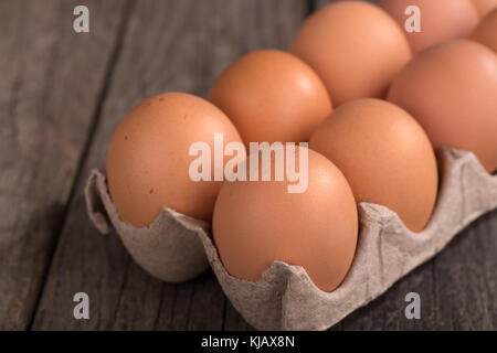 Nahaufnahme der braune Eier in einem Karton auf einer hölzernen Oberfläche Stockfoto