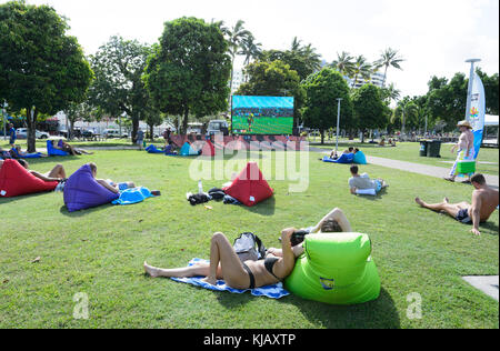 Menschen gemütlich beobachten ein Rugby-spiel auf einem riesigen TV-Bildschirm von Ihren aufblasbares Sofa auf Cairns Esplanade, Far North Queensland, Australien Stockfoto