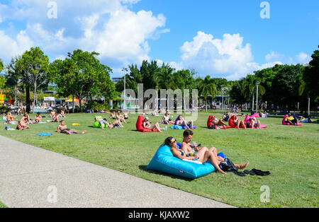 Menschen gemütlich beobachten ein Rugby-spiel auf einem riesigen TV-Bildschirm von Ihren aufblasbares Sofa auf Cairns Esplanade, Far North Queensland, Australien Stockfoto