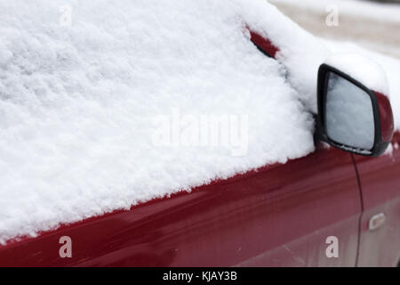 Gefrorene auto Bedeckt Schnee im Winter Tag sehen Frontscheibe Windschutzscheibe und Motorhaube auf verschneiten Hintergrund. Stockfoto