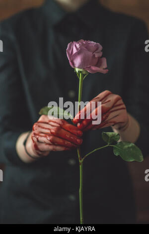 Junge Frauen, die sich in einem blutigen Rose Stockfoto