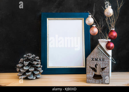 Blau goldene Rahmen mock up Weihnachten Neujahr Tannenzapfen bunte Kugeln Inhaber Kerze mit Engel Abbildung Schwarze Schiefertafel Wand leeren Raum für Angebote le Stockfoto