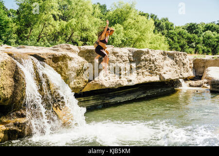 Kaukasische paar Sprung von Felsen in der Nähe von Wasserfällen Stockfoto