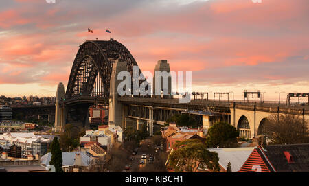 Panoramabild der Sydney Harbour Bridge, wie es war von der Observatory Hill während der dramatischen gelb und rosa Sonnenuntergang gesehen. Stockfoto