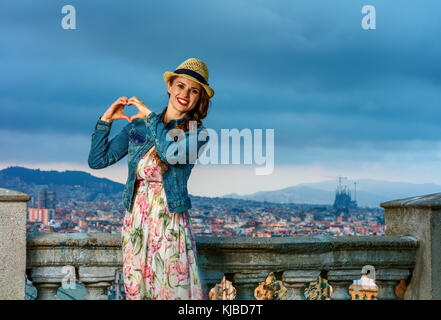 Perfekter Abend mit atemberaubenden Blick. lächelnd Elegante reisenden Frau im langen Kleid und Strohhut im Stadtbild von Barcelona, Spanien, Stockfoto