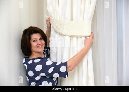 Frau setzt Klemmen auf Vorhänge Stockfoto