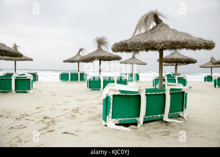 Tiki Sonnenschirme und Liegestühle am Strand, Canyamel, Mallorca, Spanien Stockfoto