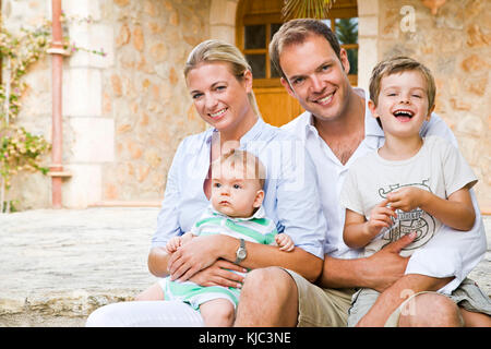 Familie sitzt vor dem Haus Stockfoto