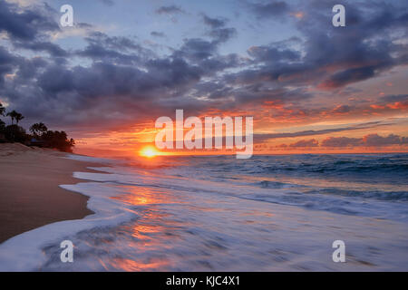 Sonnenuntergang und Surfen am Pazifik am Sunset Beach auf Oahu, Hawaii, USA Stockfoto