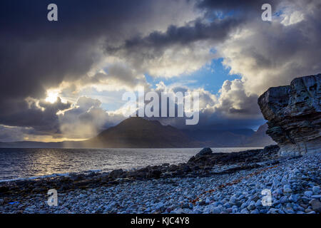 Schottische Küste mit der Sonne, die durch die dramatischen Wolken über Loch Scavaig auf der Isle of Skye in Schottland bricht, Vereinigtes Königreich Stockfoto