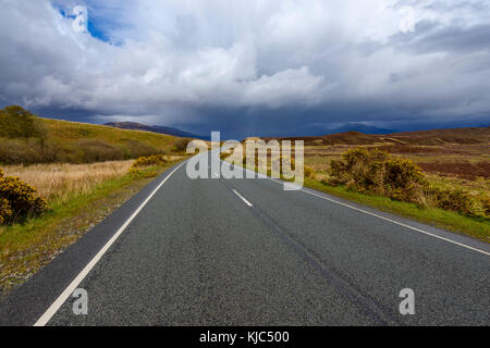 Landstraße mit dramatischen Wolken im Frühling auf der Isle of Skye in Schottland, Großbritannien Stockfoto