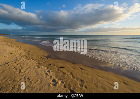 Sandstrand und dramatische Wolken über der Brandung der Nordsee bei Bamburgh in Northumberland, England, Großbritannien Stockfoto