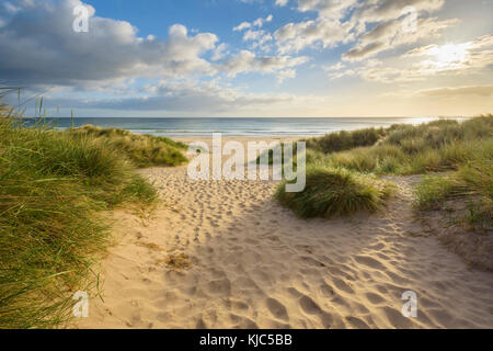 Fußspuren im Sand entlang des Weges am Strand bei Sonnenaufgang, Nordsee in Bamburgh in Northumberland, England, Großbritannien Stockfoto