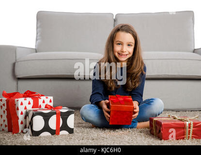 Gerne kleine Mädchen zu Hause öffnen Weihnachtsgeschenke Stockfoto