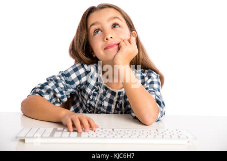 Kleines Mädchen sitzt auf einem Schreibtisch und das Arbeiten mit einem Computer Stockfoto