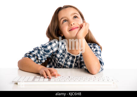 Kleines Mädchen sitzt auf einem Schreibtisch und das Arbeiten mit einem Computer Stockfoto