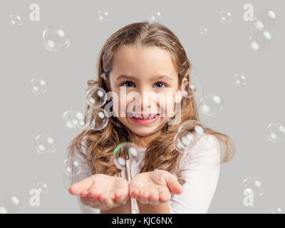 Süße kleine Mädchen spielen mit Seifenblasen Stockfoto