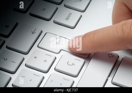 Zeigefinger drücken der ENTER-Taste an der Tastatur. Lichteffekt auf Tastatur verblassen. Konzept ein. Stockfoto