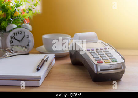 Kreditkarte terminal oder Edc auf Kassierer Holztisch im Store mit Taschenrechner, Uhr, Kreditkarten und Laptop auf Holz-/Technologie und Markt Konz Stockfoto
