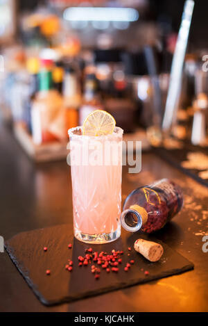 Blended alkoholfreien Cocktail mit Granatapfel in einem hohen Glas serviert mit Zucker frosted Rim auf einer hölzernen Tresen mit offenen Flasche und Zutaten gekühlt Stockfoto
