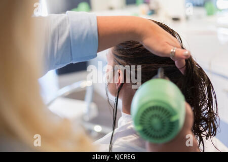 Stylist trocknen die Haare der Frau Stockfoto