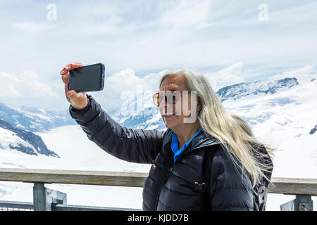 Kaukasische Frau für Handy selfie in der Nähe von Snowy Mountains posing Stockfoto