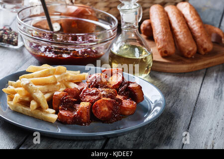 Traditionelle deutsche Currywurst - Stücke Wurst mit Curry-Sauce und Pommes frites Stockfoto