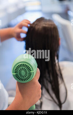 Kaukasische stylist trocknen die Haare der Frau Stockfoto