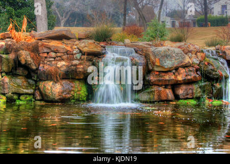 Ein Foto der Silky Falls im Dallas Arboretum in Texas, das üppige Grün und das kaskadierende Wasser der Wasserfälle zeigt. Das Arboretum bietet eine vielfältige Pflanzenwelt und ist eine wichtige Attraktion in der Region. Stockfoto