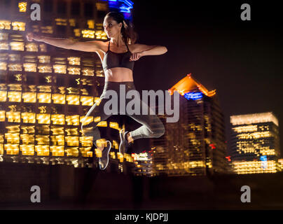 Double Exposure der kaukasischen Frau springen in Stadt bei Nacht Stockfoto