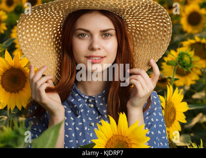 Lächelnd kaukasische Frau mit Hut im Feld mit Sonnenblumen Stockfoto