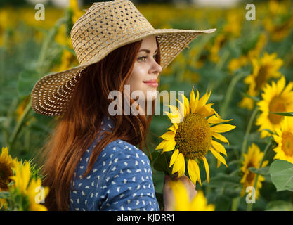 Lächelnd kaukasische Frau mit Hut im Feld mit Sonnenblumen Stockfoto