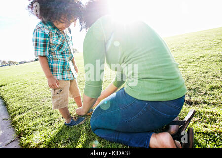 Mischlinge Mutter binden Schuh des Sohn Stockfoto