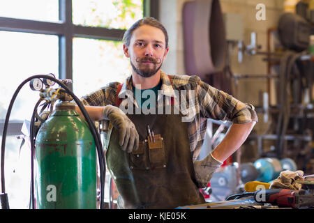 Zuversichtlich kaukasischen Mann lehnte sich auf Gas Tank in der Werkstatt Stockfoto