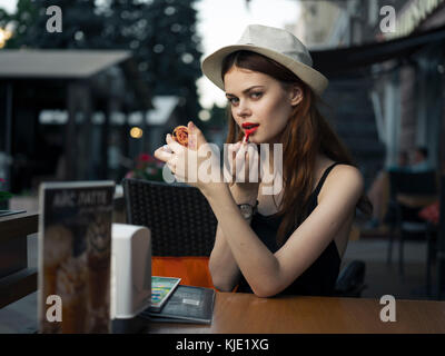 Kaukasische Frau an Sidewalk Cafe Anwendung Lippenstift Stockfoto