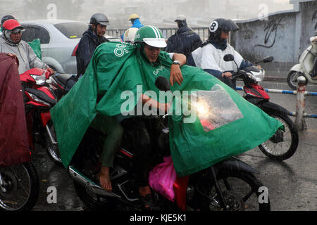 HO CHI MINH STADT, VIET NAM, Gruppe von asiatischen Menschen tragen Regenmantel Fahrt Motorrad, schwierige Bewegung in starken Regen, hoher Wind von schlechtem Wetter Stockfoto