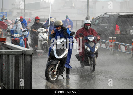 HO-CHI-MINH-STADT, Vietnamesen tragen Regenmantel, Motorrad fahren, schwierige Bewegung bei starkem Regen, starker Wind durch schlechtes Wetter durch tropischen Tiefdruck Stockfoto