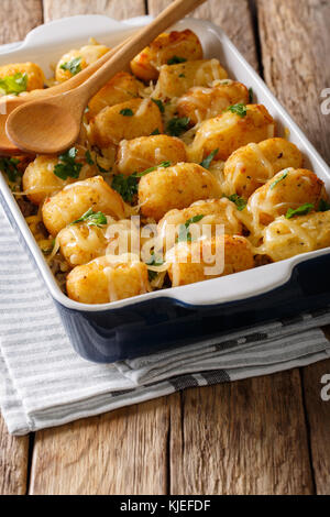 Hausgemachte gebackene Tater Tots mit Käse-, Fleisch- und Grünen schließen in einer Auflaufform auf den Tisch. Vertikale Stockfoto