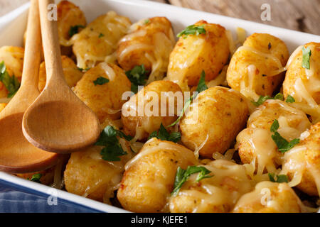 Gebackene Tater Tots mit Käse und Kräutern aus der Nähe in einer Schüssel Auflaufform auf den Tisch. Horizontale Stockfoto