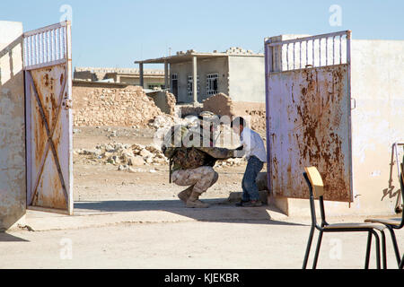 Eine italienische Armee Soldat 3. Alpine Regiment zugeordnet, eingesetzt zur Unterstützung der Operation inhärenten Lösen, und einem irakischen Terrorismus Service Mitglied kitzelt Ein irakischer Student an einer Grundschule im Dorf von Babinet, Irak, Nov. 14, 2017. Die Breite und Vielfalt der Koalitionspartner zeigt die globalen und einheitlichen Ziel der Sieg über ISIS im Irak und in Syrien. CJTF-OIR ist die globale Koalition zu besiegen ISIS im Irak und in Syrien. (U.S. Armee Foto von Sgt. Tracy McKithern) Stockfoto