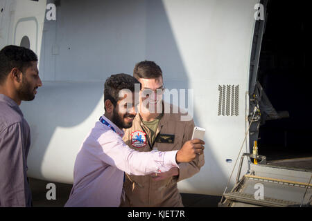 UBAI WORLD CENTRAL FLUGHAFEN, VEREINIGTE ARABISCHE EMIRATE - Kapitän John Nance, B ein MV-22 Osprey Pilot mit Marine Medium Tiltrotor Squadron 161 (verstärkt), 15 Marine Expeditionary Unit nimmt eine "selfie" mit einem Besucher bei einer statischen Anzeige an der Dubai Airshow, Nov. 14, 2017. Der fischadler ist eine gemeinsame Dienstleistung Mehrzweck-kampfflugzeug Nutzung tiltrotor Technologie der vertikalen Leistung von einem Hubschrauber mit der Geschwindigkeit und Reichweite eines Flugzeugen in globale Reichweite Fähigkeiten, die es ihm erlauben, eine Nische im Gegensatz zu anderen Luftfahrzeugen zu füllen, die sich zu kombinieren. Die Dubai Airshow ist das Prem Stockfoto