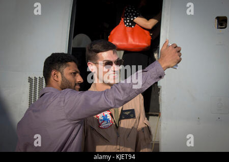 UBAI WORLD CENTRAL FLUGHAFEN, VEREINIGTE ARABISCHE EMIRATE - Kapitän John Nance, B ein MV-22 Osprey Pilot mit Marine Medium Tiltrotor Squadron 161 (verstärkt), 15 Marine Expeditionary Unit nimmt eine "selfie" mit einem Besucher bei einer statischen Anzeige an der Dubai Airshow, Nov. 14, 2017. Der fischadler ist eine gemeinsame Dienstleistung Mehrzweck-kampfflugzeug Nutzung tiltrotor Technologie der vertikalen Leistung von einem Hubschrauber mit der Geschwindigkeit und Reichweite eines Flugzeugen in globale Reichweite Fähigkeiten, die es ihm erlauben, eine Nische im Gegensatz zu anderen Luftfahrzeugen zu füllen, die sich zu kombinieren. Die Dubai Airshow ist das Prem Stockfoto