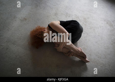 Kaukasische Frau Festlegung auf konkrete in der fetalen Position Stockfoto