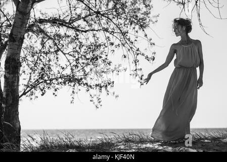 Kaukasische Frau trägt ein Kleid in der Nähe von Tree Stockfoto