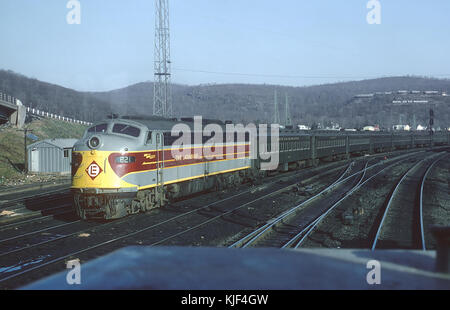 Dieses Foto zeigt die EL E8A 821-Lokomotive auf der Werft Suffern, NJ am 25. April 1970. Das Bild bietet einen detaillierten Blick auf die Lokomotive, da sie Teil eines Güterzugs ist, der die technischen Aspekte des Zuges und seinen Kontext innerhalb der historischen Umgebung unterstreicht. Stockfoto