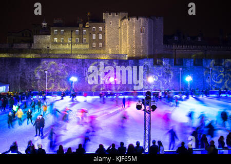 Leute Eislaufen in der Nacht auf einem farbigen Eisbahn in die Vorderseite von Turm von London während der Weihnachtszeit - London, Großbritannien Stockfoto