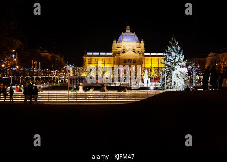 Zagreb, Kroatien: 30 decemer 2015: Eislaufbahn an ledeni Park in der Nacht im Winter mit Blick auf den Pavillon mit Besucher Skaten rund um den Springbrunnen Stockfoto